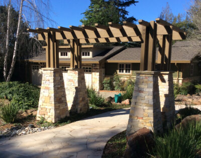 Wood and stone trellis leading entry path to a house