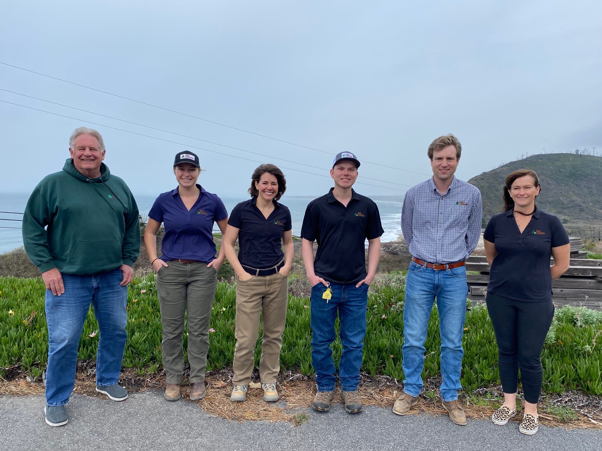 Team of people standing in a line with the ocean in the background