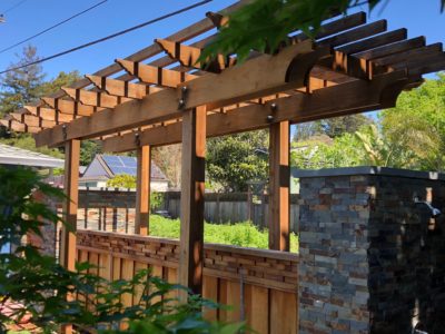 Backyard wood trellis with stone work and some greenery