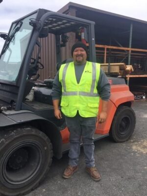 Man in safety vest standing in front of fork lift