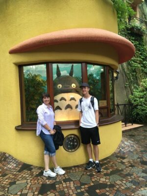 Man and woman standing in front of a yellow building with a window