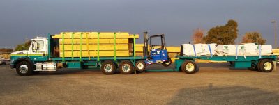 Truck with trailer filled with lumber and a forklift.