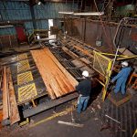 A sawmill worker feeding an even flow of boards to the trim saw.